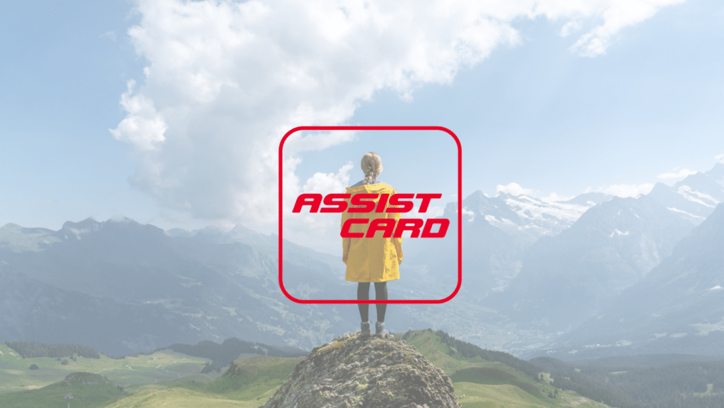 Uma mulher em cima de uma pedra de frente para diversas montanhas com o logo da empresa Assist Card no centro da imagem