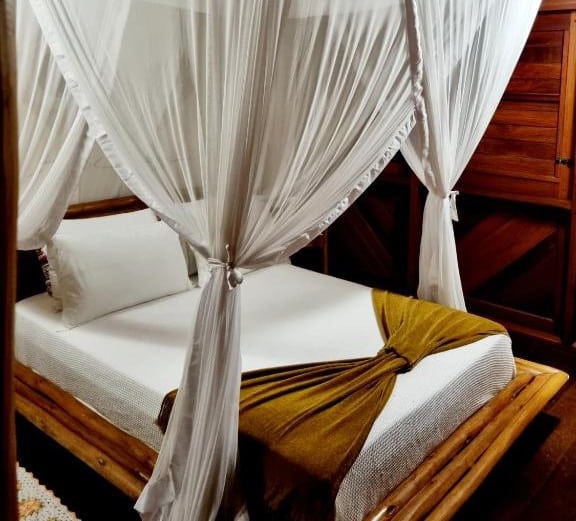 Quarto do Bangalô alto do Mucugê. Uma cama de cassal é rodeada por panos, como um dossel.