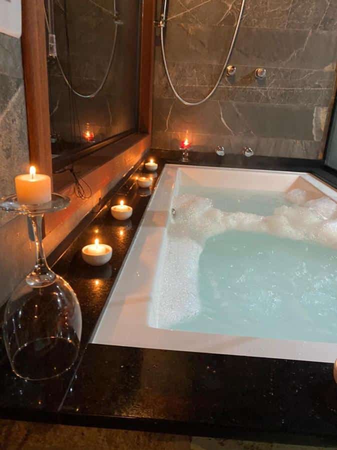 Banheira de hidromassagem do Bangalô dos Alpes de São Chico com velas ao redor.