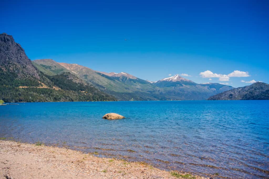 O Lago Gutíerrez, e Bariloche, com uma pedra no meio e ao redor lindas montanhas.