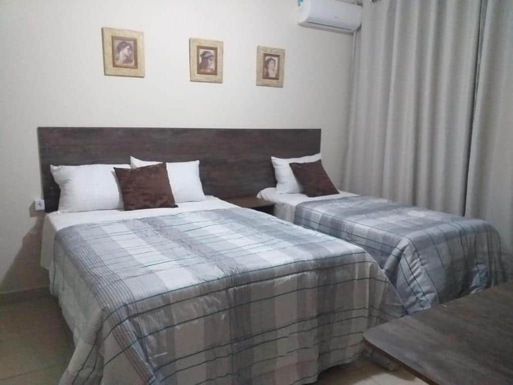 Quarto do Caldas Novas Residence. Uma cama de casal do lado esquerdo, do lado direito uma cama de solteiro, em cima um ar-condicionado. Foto para ilustrar post sobre airbnb em Caldas Novas.