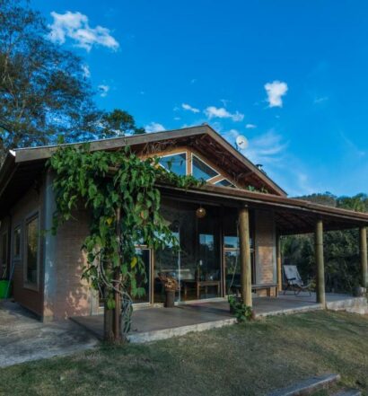Área externa da Casa da Montanha para ilustrar post sobre airbnb em Santo Antônio do Pinhal. Ao redor as montanhas, no meio a casa com varanda.