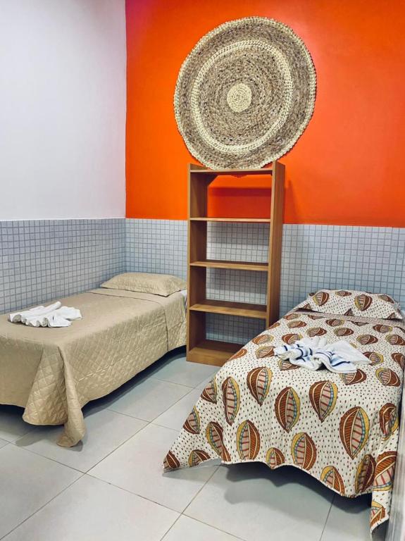 Quarto da Casa Da Didda. Uma cama de solteiro de cada lado. No meio, uma estante com prateleiras. Foto para ilustrar post sobre airbnb em Fernando de Noronha.