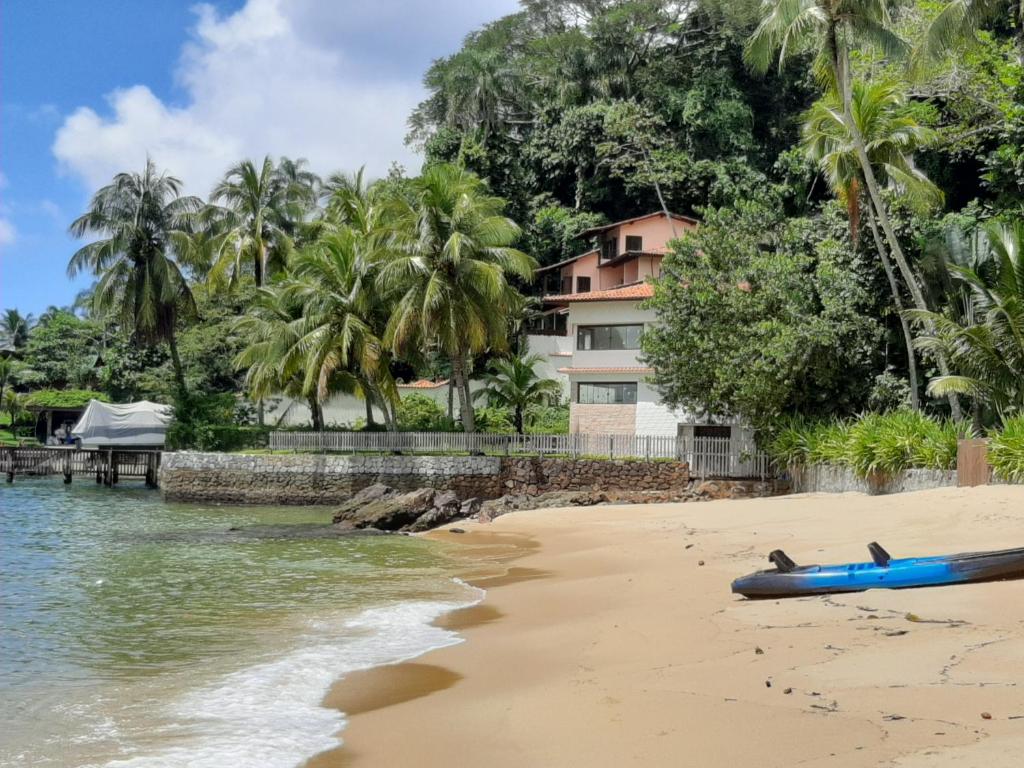 Casa de temporada vista da praia. Em volta da casa há uma vegetação com árvores e coqueiros e no lado esquerdo está o mar. Imagem para ilustrar o post airbnb em Angra dos Reis.