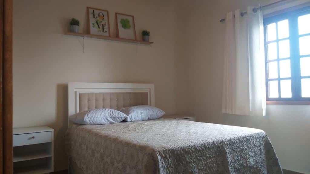 Quarto da Casa na Serra 156. Uma cama de casal no meio, de cada lado uma cômoda. Do lado direito uma janela. Foto para ilustrar post sobre airbnb em Santo Antônio do Pinhal.