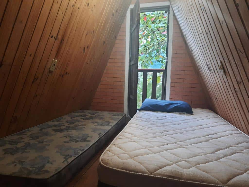Quarto do Chalés Monções. Do lado direito um colchão de casal, do lado direito um colchão de solteiro, no fundo a porta aberta. Foto para ilustrar post sobre airbnb em Perequê Mirim.