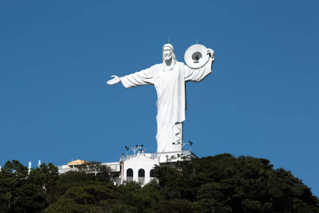 O Cristo Luz no meio, durante o dia, ao redor árvores. 