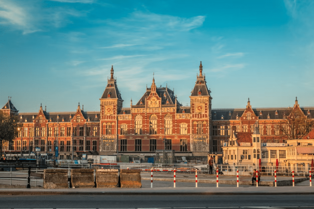 Vista de frente da Estação Central de Amsterdam, um prédio imponente e muito detalhado em estilo tradicional e tons terrosos e dourados