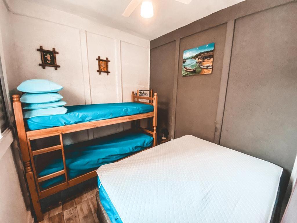 Quarto do kitnets EBENÉZER 3 Praias. Uma cama de casal do lado direito, do lado esquerdo uma cama de beliche com travesseiros. Foto para ilustrar post sobre airbnb em Perequê Mirim.