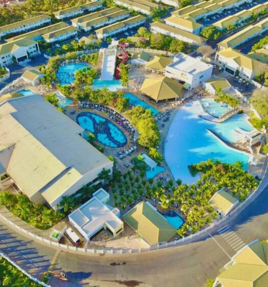 Imagem de cima do L'acqua diroma I, II, III, IV e V para ilustrar post sobre airbnb em Caldas Novas. Um hotel do lado esquerdo, do lado direito várias piscinas e caminhos com árvores.