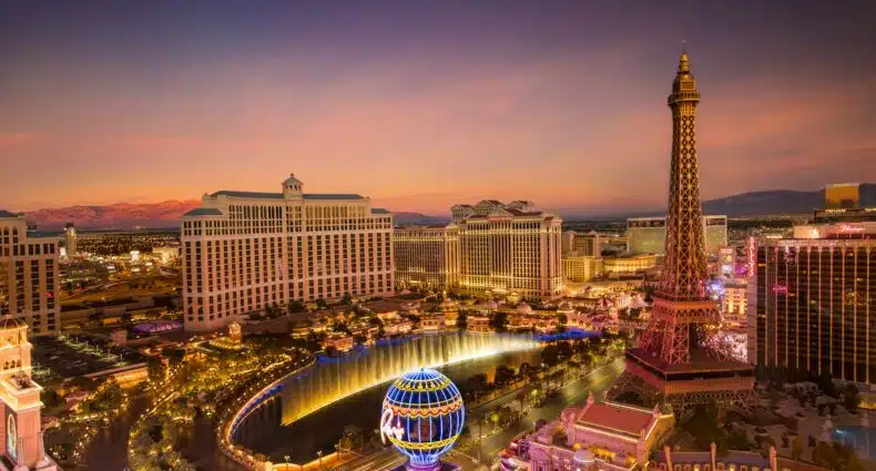 Foto panorâmica de toda Las Vegas Strip tirada de longe. Ela mostra a torre eiffel e o balão gigante do Paris Las Vegas no canto direito e a fonte do Bellagio no meio. Todo o resto do ambiente são hotéis e ruas. A imagem ilustra o post de pontos turísticos em Las Vegas.