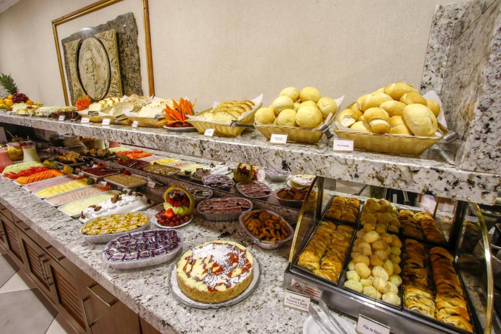 Bancada do café da manhã no Life Hotel Infinity. Uma mesa com pães, frios, frutas e doces.