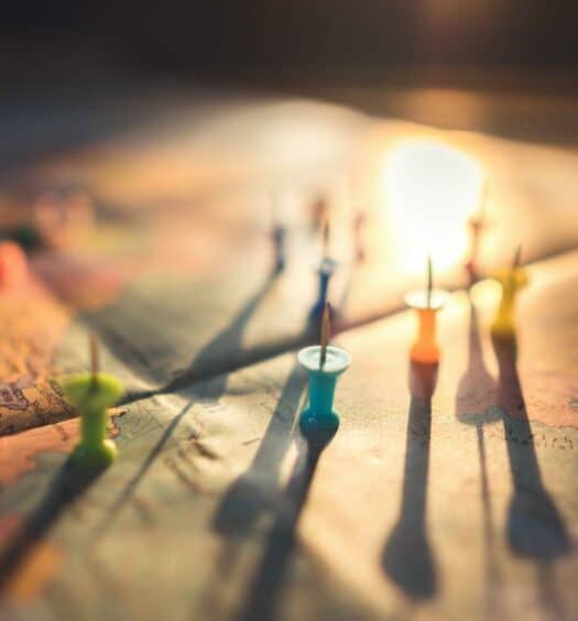 Luz do sol iluminando um mapa da Europa com alfinetes coloridos virados para cima. A imagem ilustra o post sobre Tratado de Schengen. - Foto: Aksonsat Uanthoeng via Pexels