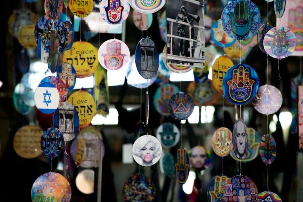 plaquinhas coloridas e redondas com diversas estampas diferentes, que mesclam cultura pop com símbolos religiosos, no Mercado Carmel, em Tel Aviv, Israel