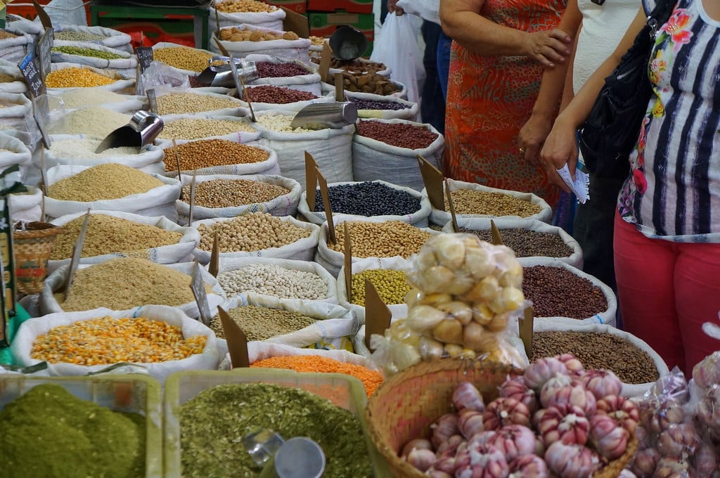 Várias cestas de grãos no Mercado Municipal de Curitiba. Do lado direito pessoas olhando. Imagem para ilustrar post sobre o que fazer em Curitiba.