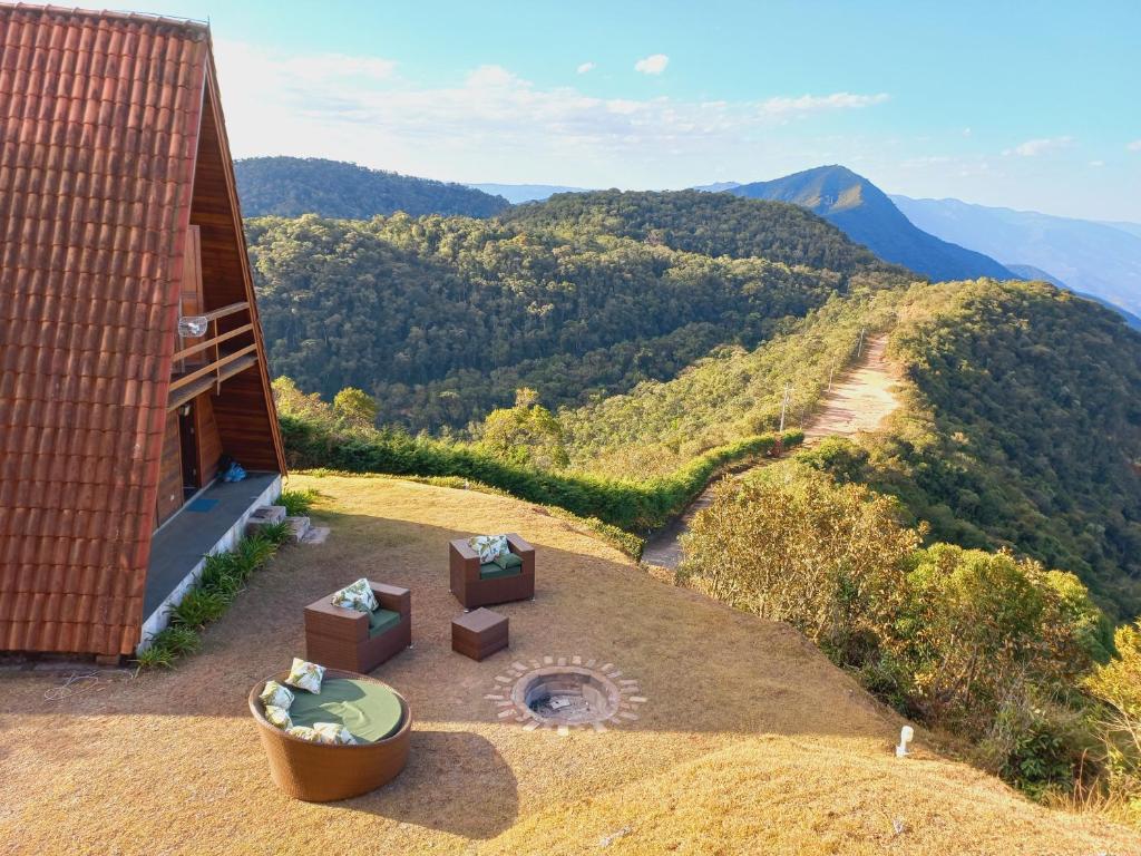 Área externa do Mirante 45. Do lado direito as montanhas, no meio uma lareira de chão, ao redor sofás. No lado esquerdo o chalé.