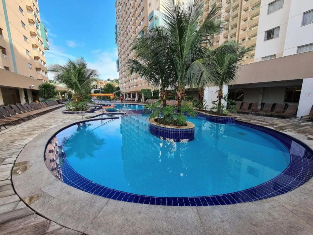 Área de lazer do Olímpia Park Resort para ilustrar post sobre airbnb em Olímpia. Uma piscina no meio com uma palmeira, ao redor os prédios.