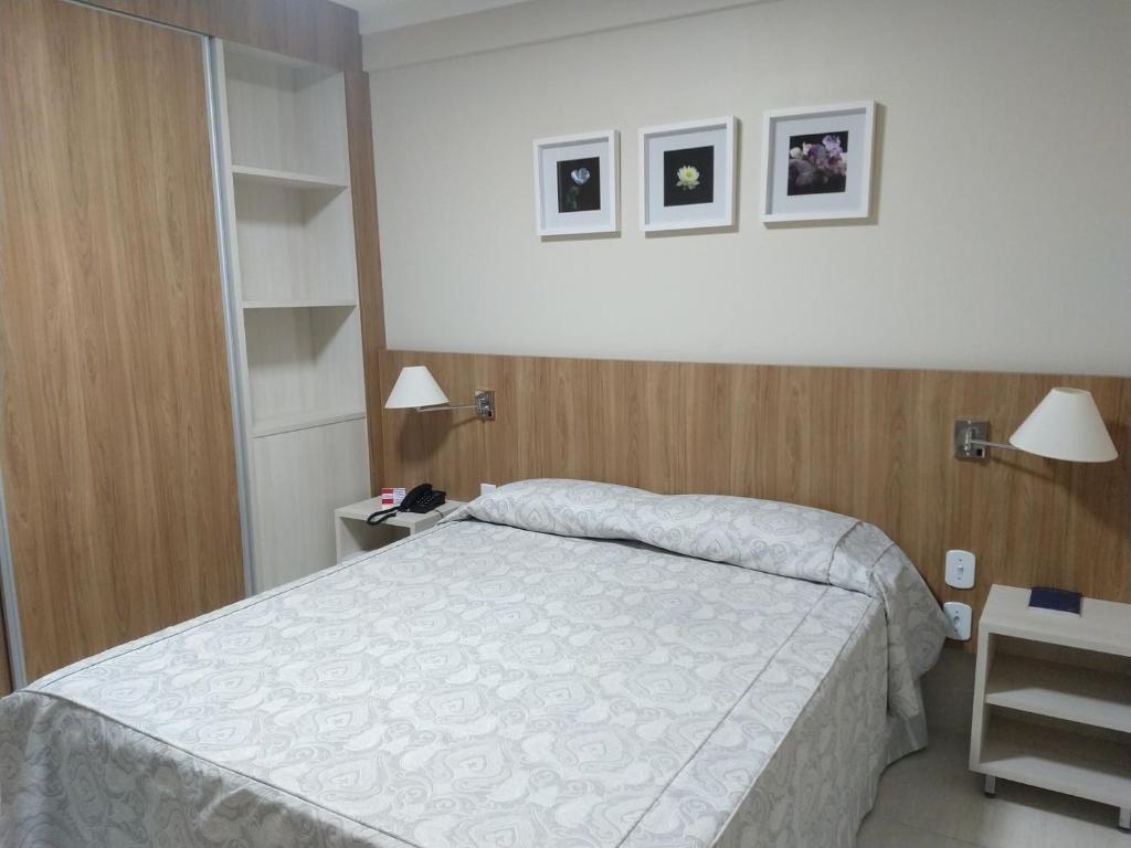 Quarto do Piazza diRoma - Apartamentos JN. Uma cama de casal no meio, de cada lado uma mesinha de apoio e um abajur. Do lado esquerdo um guarda-roupa.
