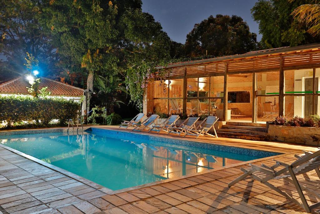 piscina retangular à noite com iluminação no Solar dos Ipês, uma das pousadas na Serra do Cipó, com espreguiçadeiras e espaço coberto