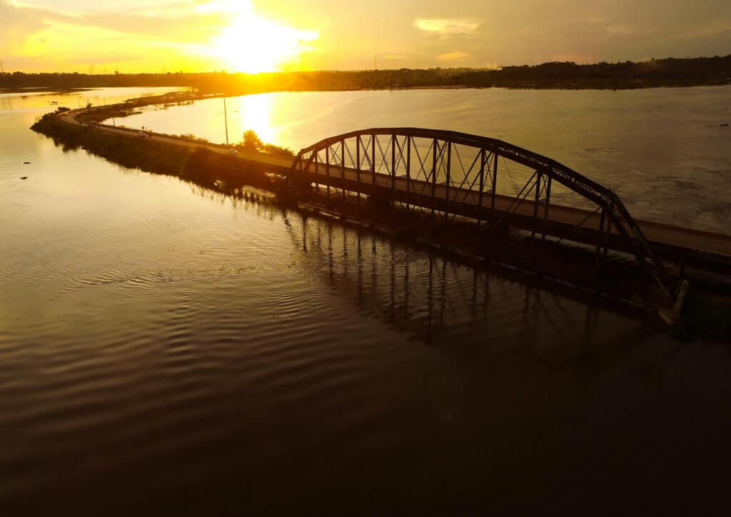 Foto de Porto Velho. Um rio e em cima de uma ponte extensa, com visão do pôr do sol.