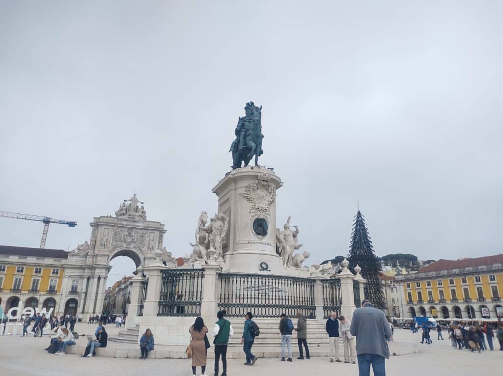Imagem da Praça do Comércio de uma estátua com um homem em cima de um cavalo durante o dia.