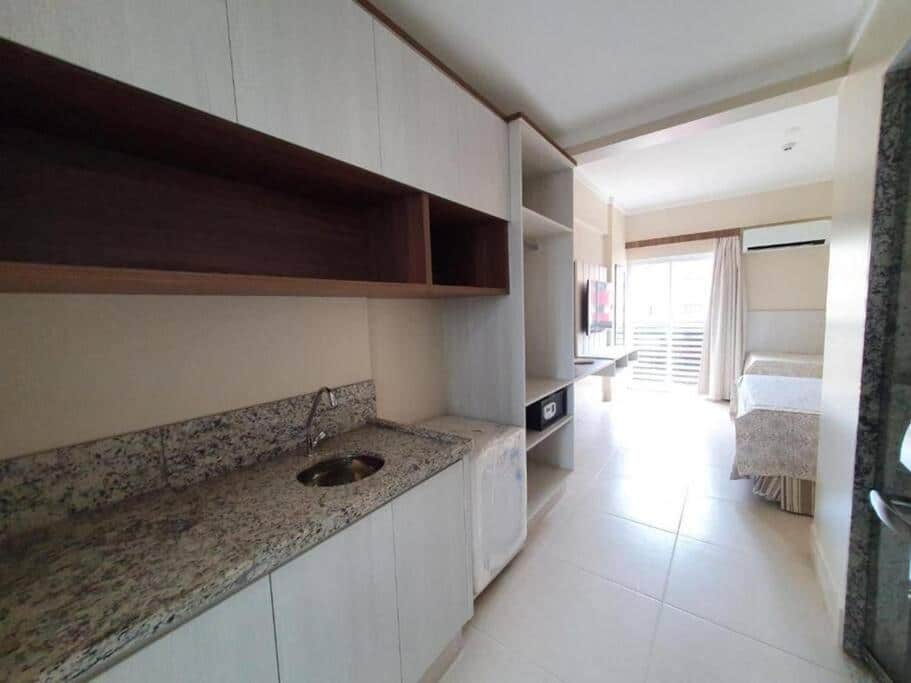 Quarto do Spazzio Diroma - Acqua Park Splach e Slide. Do lado direito armários, uma pia e um frigobar. No fundo, do lado esquerdo um painel com televisão, do lado direito uma cama de casal e uma de solteiro, com um ar-condicionado no fundo.