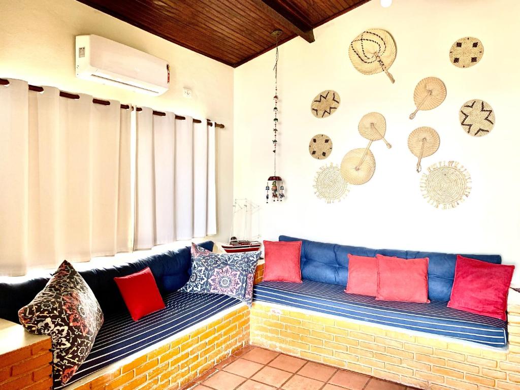 Sala de estar do Ubatuba casa frente mar. Um sofá cama no meio e outro do lado esquerdo. Em cima, uma janela com cortina fechada. Foto para ilustrar post sobre airbnb no centro de Ubatuba.