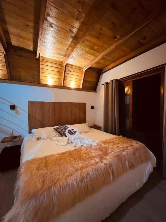 Quarto do Villa Itália. Uma cama de casal no meio, com decoração com toalha em cima. Do lado direito a porta para a varanda. Foto para ilustrar post sobre airbnb em Santo Antônio do Pinhal.