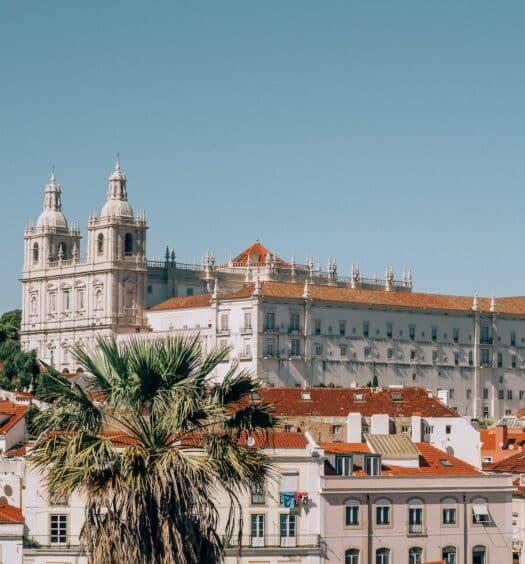 vista do bairro de Alfana, em Lisboa, Portugal, com várias casinhas e uma igreja grande em tons claros e telhados marrons