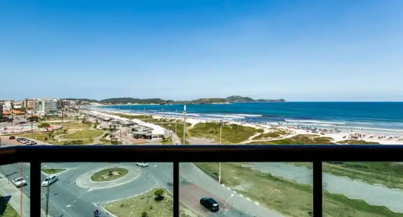 Varanda do Apart Hotel Porto Príncipe. Na parte inferior da imagem é possível ver o parapeito da varanda e na parte superior a vista é para a Praia do Forte. Imagem para ilustrar o post airbnb em Cabo Frio.
