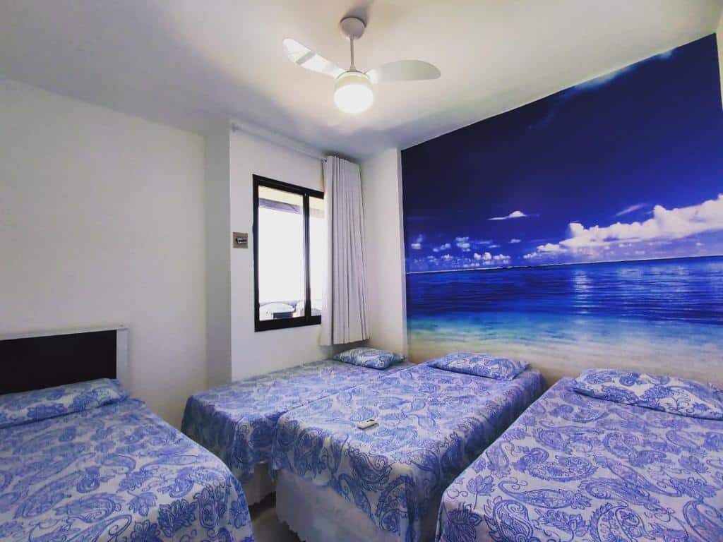Quarto do Apartamento vista mar Atalaia. Três camas de solteiro do lado direito, de frente mais uma cama de solteiro. No fundo uma janela. Foto para ilustrar post sobre airbnb em Aracaju.