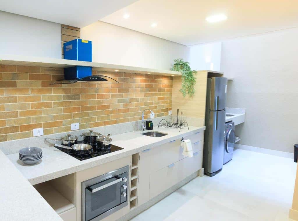 Cozinha completa e espaçosa do Apartamento completo – Vila A Há uma bancada com armários, fogão, forno, pia, geladeira e máquina de lavar.