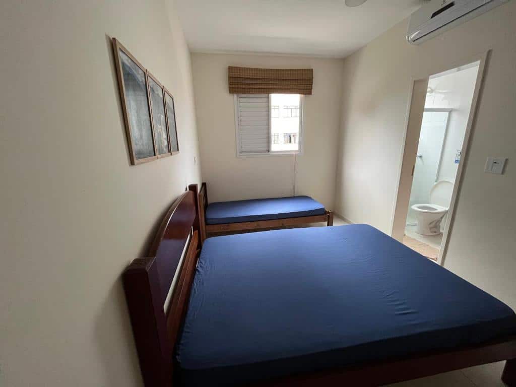 Quarto do Apt 2 suites. Uma cama de casal e no fundo uma cama de solteiro, em cima a janela. Do lado direito a porta do banheiro. Foto para ilustrar post sobre airbnb em Itaguá.
