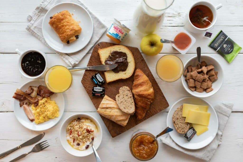 Café da manhã do B&B HOTEL Orly Rungis Aéroport 3 étoiles visto de cima com itens como pães, sucos, frutas e laticínios.