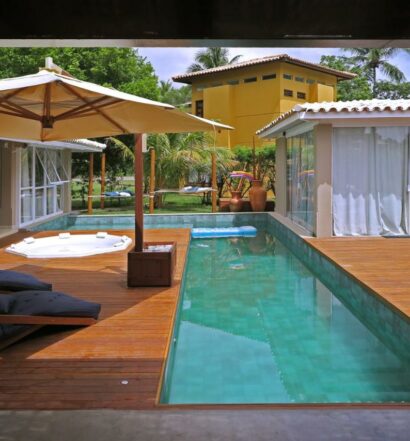 Vista da piscina do Beach House Sauípe durante o dia com piscina do lado direito da imagem e do lado esquerdo cadeiras. Representa airbnb na Costa do Sauípe.