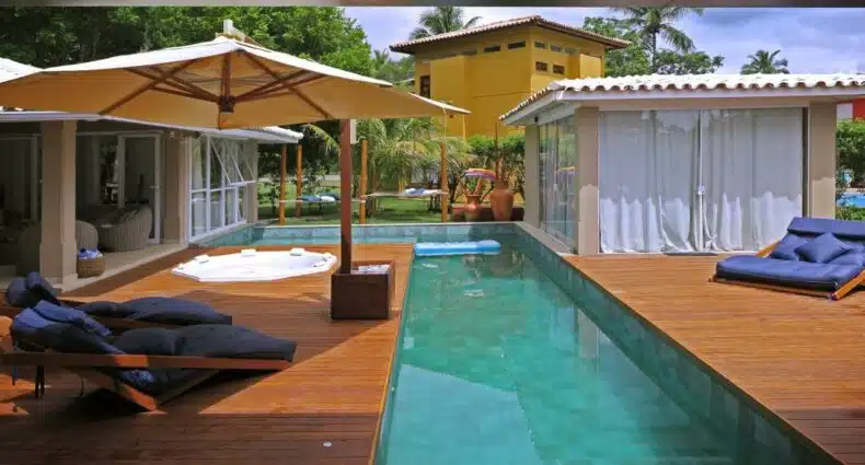 Vista da piscina do Beach House Sauípe durante o dia com piscina do lado direito da imagem e do lado esquerdo cadeiras. Representa airbnb na Costa do Sauípe.