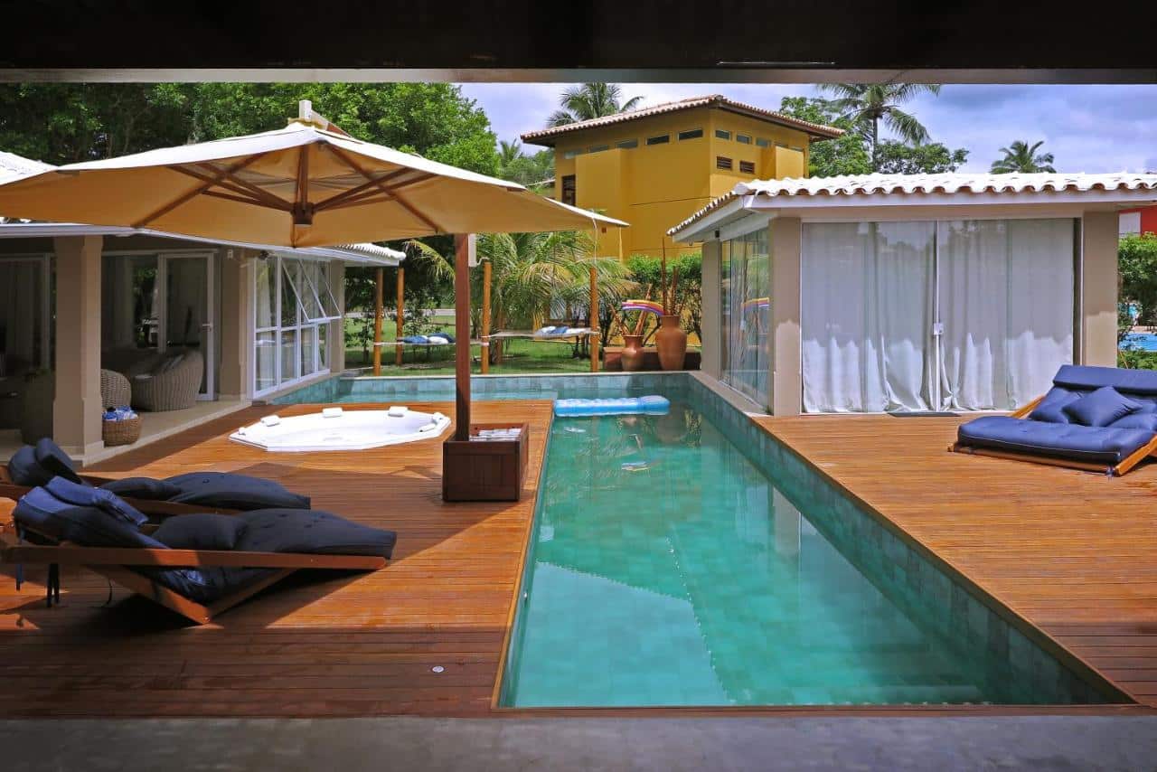Vista da piscina do Beach House Sauípe durante o dia com piscina do lado direito da imagem e do lado esquerdo cadeiras. Representa airbnb na Costa do Sauípe.