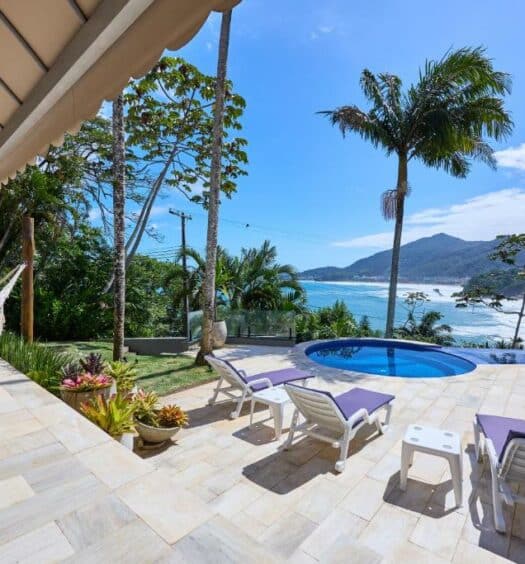 Imagem da varanda da Casa de alto padrão com ampla vista para o mar durante o dia com rede do lado esquerdo da imagem do lado direito, cadeiras com vista para a piscina e ao fundo vista para o mar. Representa airbnb na praia do Tenório.