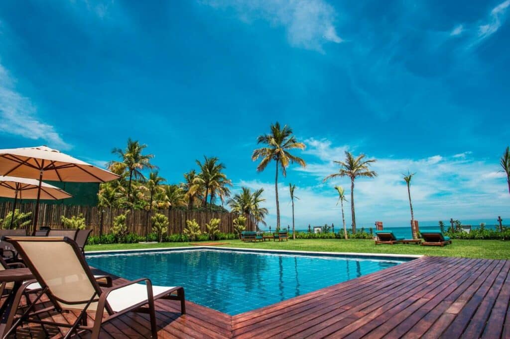 Piscina do Residencial Marina Del Sol durante o dia com cadeiras do lado esquerdo da imagem, no centro em frente a piscina. Representa airbnb na praia de Santiago.
