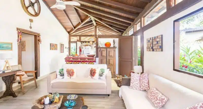 Sala de estar da Casa na Barra do Sahy com mesa de centro a frente do lado esquerdo da imagem do lado direito da imagem um sofá e atrás da mesa de centro outro sofá. Representa airbnb na Barra do Sahy.