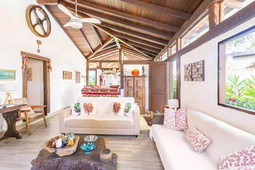 Sala de estar da Casa na Barra do Sahy com mesa de centro a frente do lado esquerdo da imagem do lado direito da imagem um sofá e atrás da mesa de centro outro sofá. Representa airbnb na Barra do Sahy.