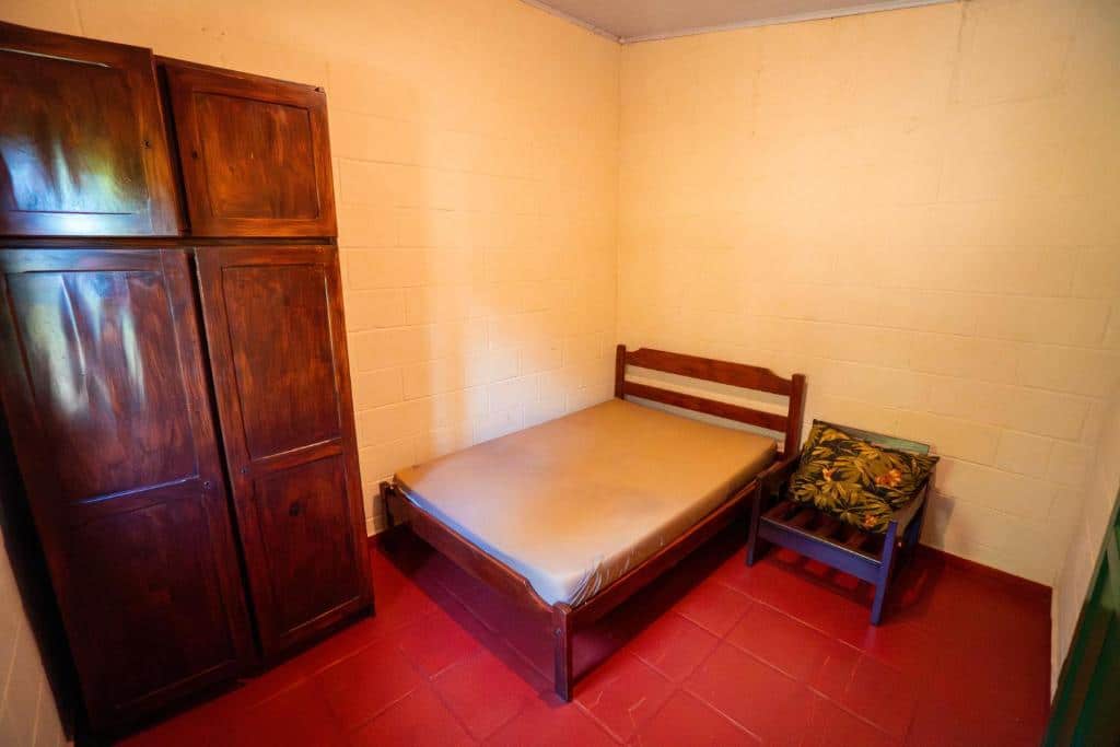 Quarto da Casa da Almada. Umm guarda-roupa do lado esquerdo, do lado direito uma cama de casal e uma cadeira pequena de madeira. Foto para ilustrar post sobre airbnb na Praia da Almada em Ubatuba.