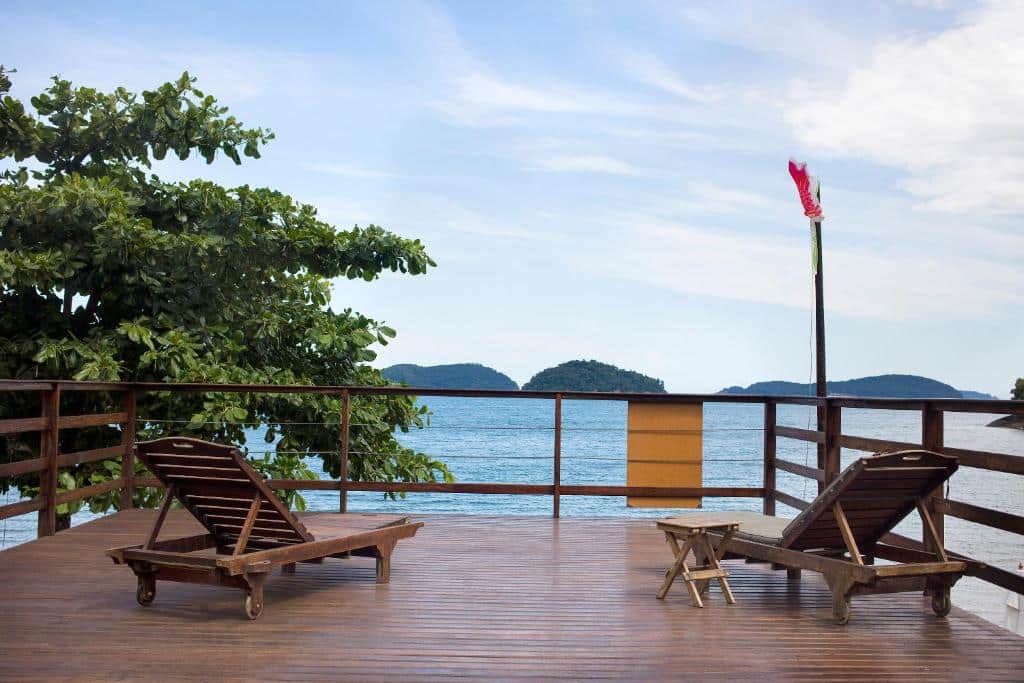 Varanda da Casa da Justa. Um deck com duas cadeiras de madeira e vista para o mar.