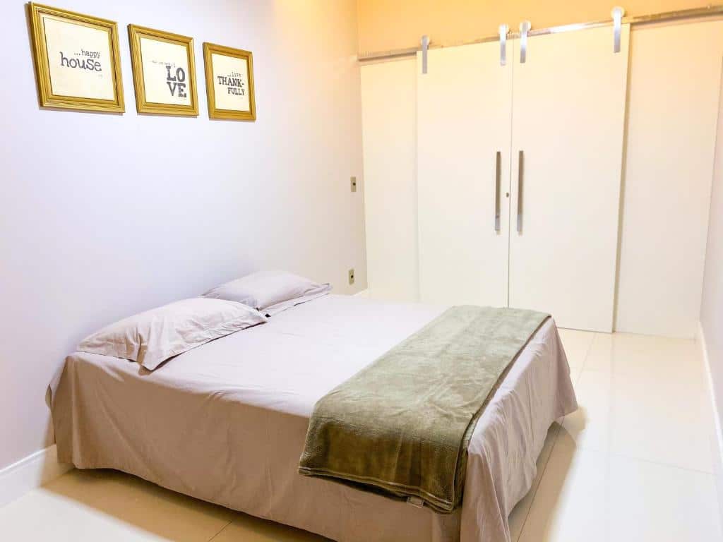 Quarto da Casa de Luxo na Praia. Uma cama de casal na frente, em cima três quadros, no fundo a porta do quarto. Foto para ilustrar post sobre airbnb em Aracaju.