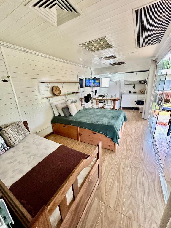 Quarto da Casa do bananal. Uma cama de solteiro no canto direito, atrás uma cama de casal, no fundo uma televisão, uma mesa e uma minicozinha. Foto para ilustrar post sobre airbnb em Ubatumirim.