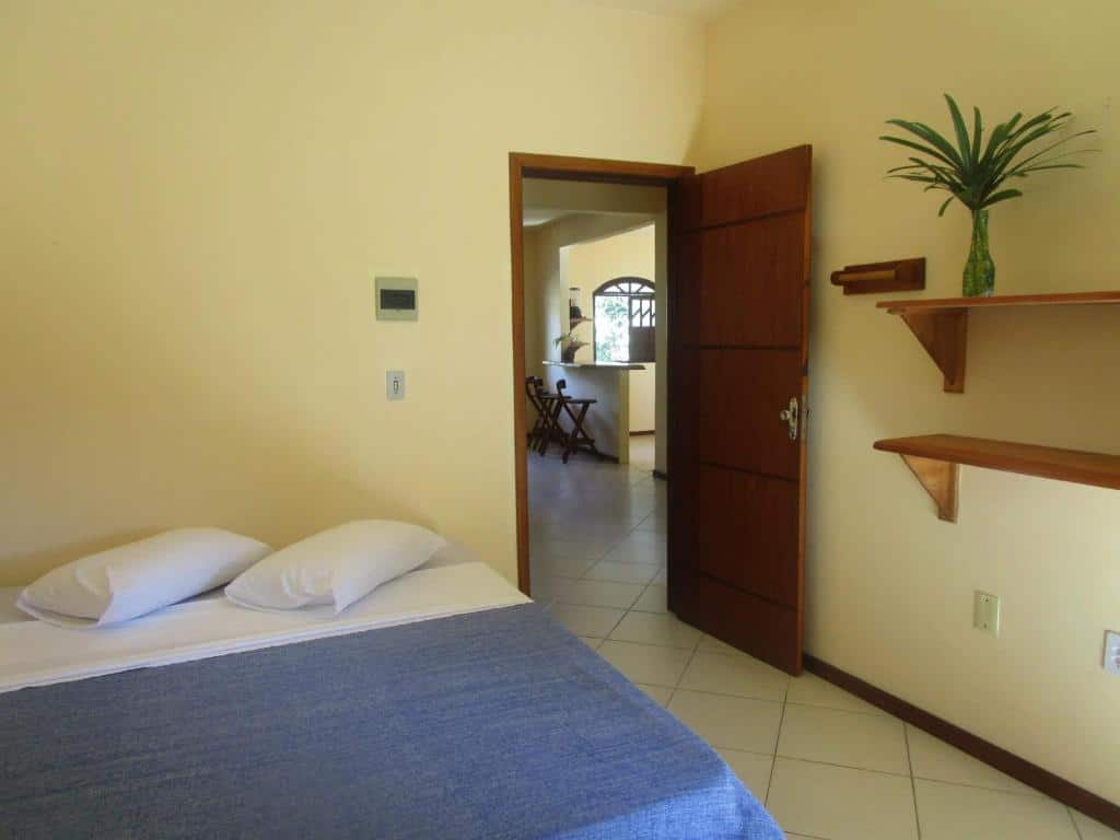 Quarto da Casa Magna.. Há uma cama box de casal à esquerda, e a porta está à direita. Ainda na direita há prateleiras na parede. Representa o post sobre airbnb em Itacaré.