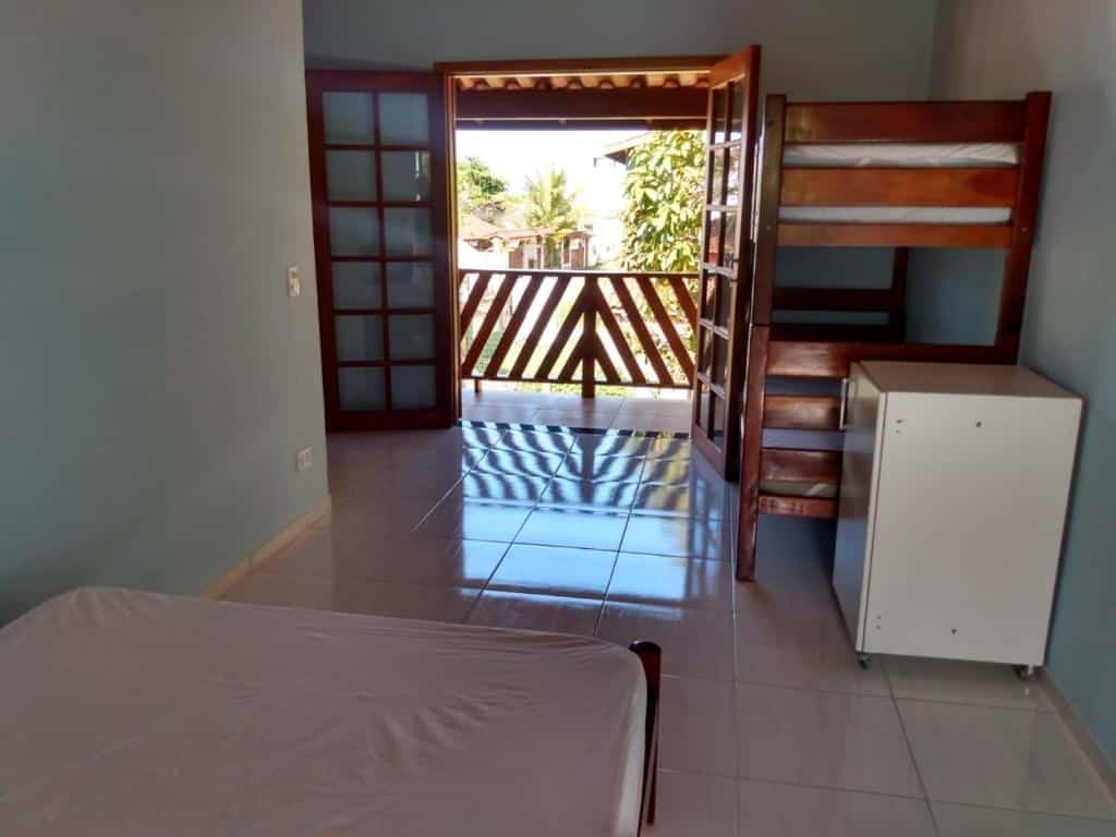 Quarto da Casa na praia do estaleiro. Uma cama de casal do lado esquerdo, do lado direito um armário e uma cama beliche. No meio a porta da varanda. Foto para ilustrar post sobre airbnb na Praia da Almada em Ubatuba.