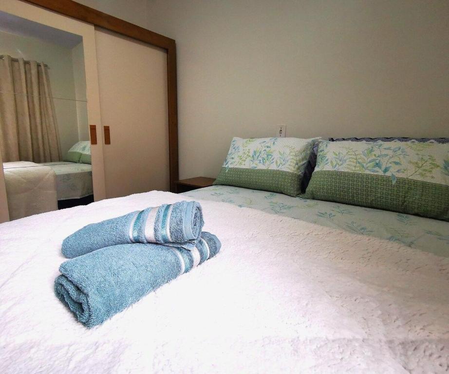 Foto do quarto na Casa próxima às Cataratas e Argentina. Há uma cama box de casal com toalhas e cima e um guarda-roupa à esquerda. Está ilustrando o post sobre airbnb em Foz do Iguaçu.