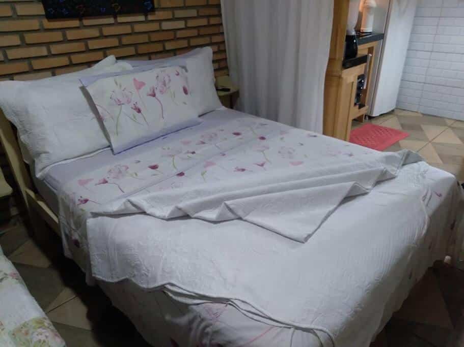 Quarto do chalé recanto Monte fuji. Uma cama de casal do lado esquerdo, no fundo uma minicozinha. Foto para ilustrar post sobre airbnb em Ubatumirim.