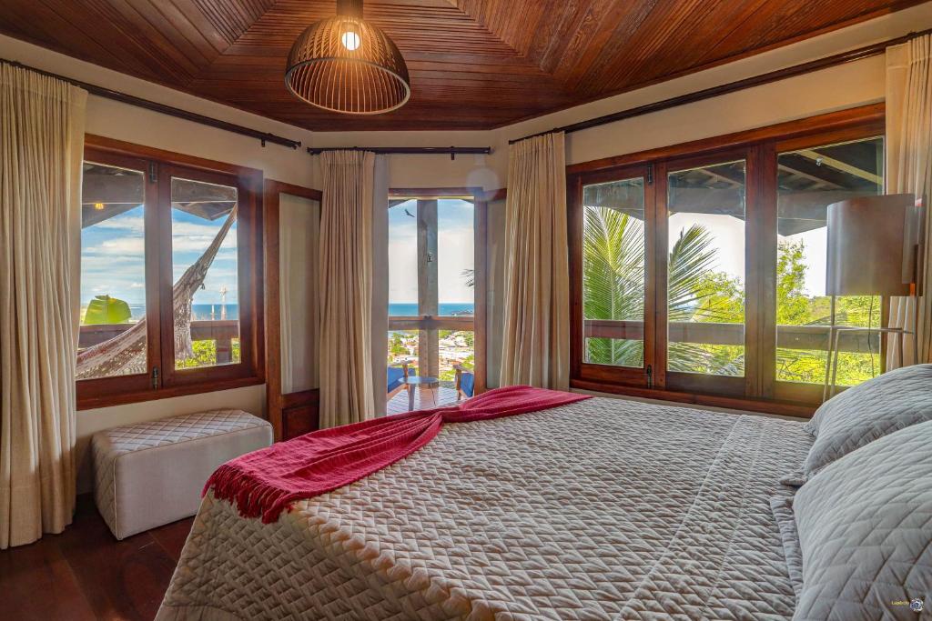 Vista diagonal do quarto do Chocolate Hotel. Vemos a cama box de casal, e a sua frente há portas e janelas com vista para a praia.